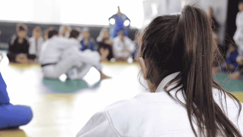 Mulher faixa branca de jiu-jitsu treinando com foco em academia moderna