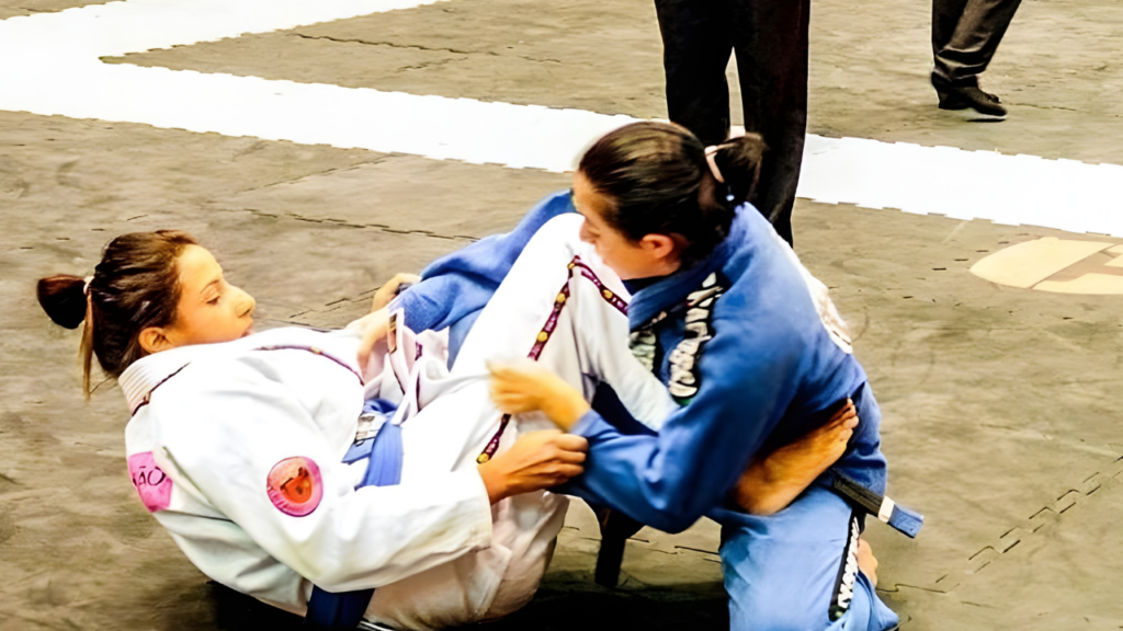 Lutadora de jiu-jitsu segurando várias faixas coloridas no tatame